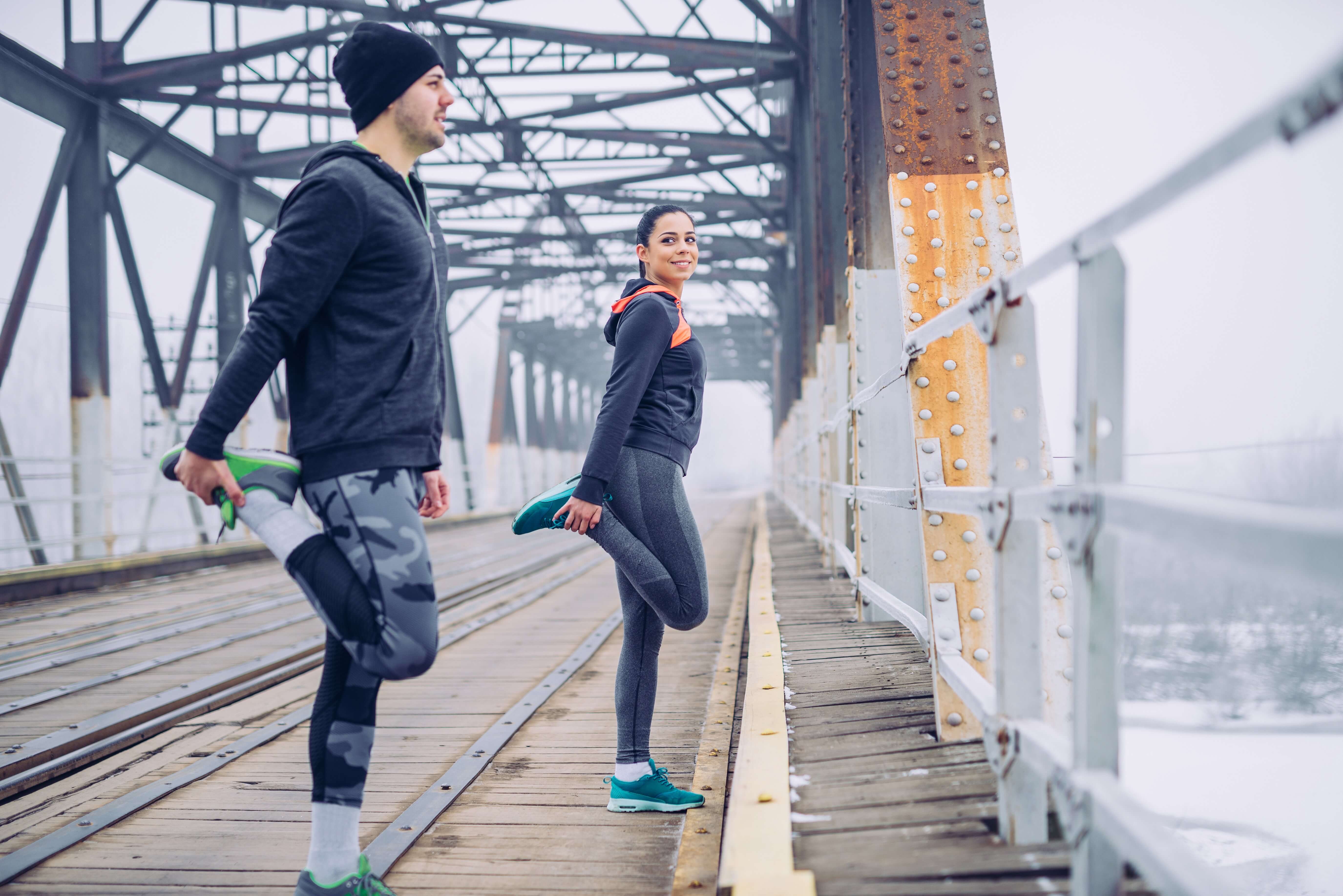Man and woman stretching outdoor in cold weather