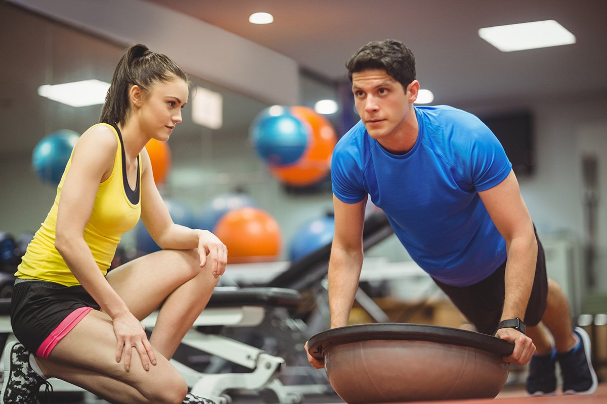 A personal trainer cueing client who is doing stabalization ball pushups
