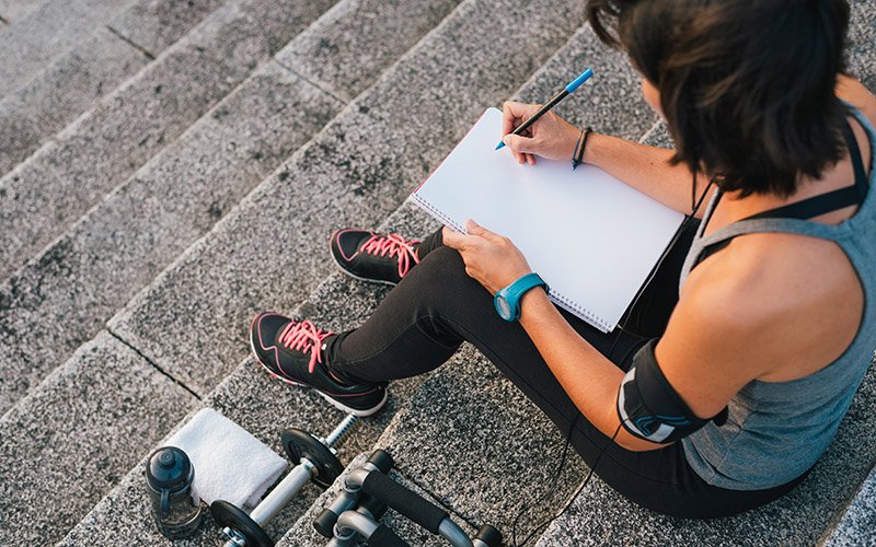 trainer setting smart fitness goals for herself with a notepad